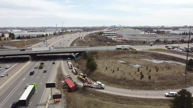 Aerial orbit overview of red semi truck flipped over on highway on ramp