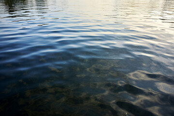 Beautiful view on the water in the daylight. At the flat surface of water gentle waves are visible created with generative AI technology