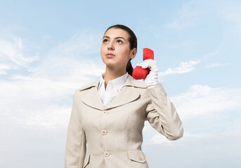 Young business woman holding red retro phone