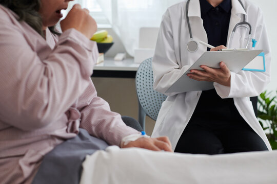 Doctor visiting sick caughing senior woman at home