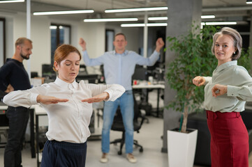 Four office workers warm up during a break. Employees do fitness exercises at the workplace. 