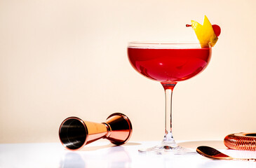 New Yorker red cocktail with whiskey, grenadine, bitter, lemon and ice garnished with lemon zest and cocktail cherry in glass. Beige background, hard light - obrazy, fototapety, plakaty