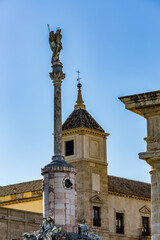 Fototapeta na wymiar Statue on high pedestal next to church of St John the Baptist, Cordoba, Andalusia, Spain