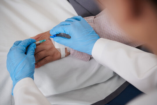 Closeup image of doctor inserting intravenous catheter in hand of patient