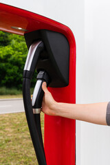 A man holds a charger plug for an electric car.