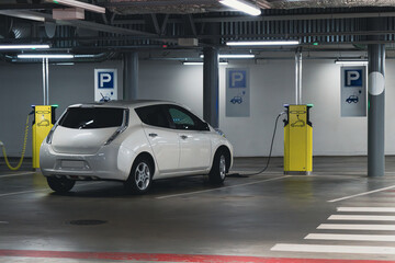 Electric cars are charged from the charging station in the indoor parking of the shopping center..