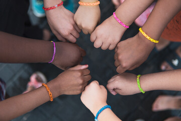 Multiethnic children hands together with rainbow bracelets. Friendship on a elementary age students...