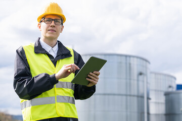 Engineer with digital tablet on a background of gas tanks