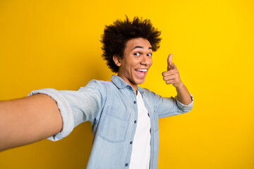 Photo of positive excited man wear jeans shirt tacking selfie showing finger you isolated yellow...