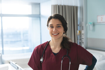 Portrait of happy caucasian female doctor with brown hair, wearing red scrubs and stethoscope