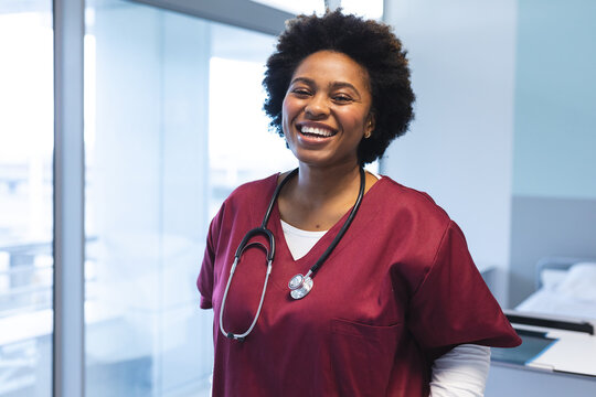 Portrait Of Happy African American Female Doctor Wearing Scrubs And Stethoscope, Smiling