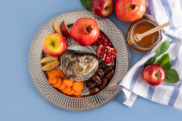 A silver dish with traditional food Rosh Hashanah. pomegranates, apples, honey, fish head, dates....