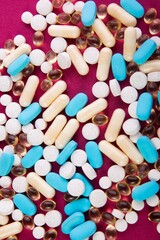 Medical pills scattered on a pink surface