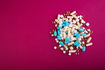 Closeup of medical pills and capsules isolated on a pink background