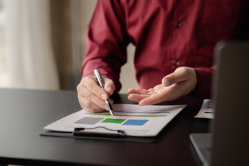 Business man pointing to a pie chart document showing company financial information, He sits in her private office, a document showing company financial information in chart form. Financial concepts.