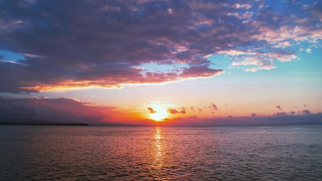 Landscape of sunset sky with clouds over the ocean. Bright orange sun in the evening sky. Sea waves with sun reflection. Calm morning seascape. Horizon over water. Breathtaking sunset over the sea.