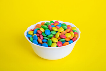 Multicolored candies in a bowl on a colored background. birthday and holiday concept. Top view with copy space