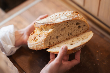 Girl checking quality of self made palianytsia bread. Fresh baked bread in hands of a hostess in...
