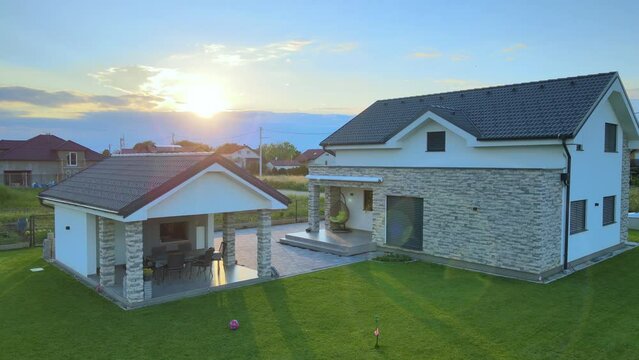 Modern smart house with two buildings units at sunrise, residential safe neighborhood. Green grass backyard aerial footage