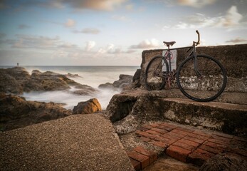 Fototapeta premium Old bike leaning against a seawall on the Gold Coast, Qld, Australia.
