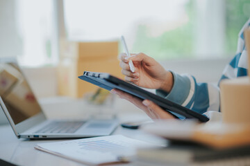 Startup small SME business entrepreneur female sitting at the desk, using digital tablet to create her online marketing content. cropped closeup image.