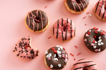 Top view of chocolate and pink donuts messily arranged on a pink surface