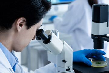A male scientist conducting research under a microscope	