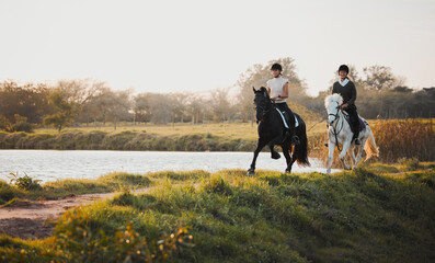 Horse riding, freedom and equestrian with friends in nature on horseback by the lake during a summer morning. Countryside, hobby and female riders outdoor together for travel, fun or adventure - Powered by Adobe
