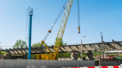 Fototapeta na wymiar Construction of a bridge for road transport. Installation of metal structures of a multi-level transport interchange. Metal span of the bridge. A crane on a construction site.