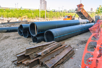 Fototapeta na wymiar Large diameter plastic pipes for outdoor water supply. Pipes made of high - density polyethylene . Smooth black plastic pipes. Laying of water supply systems.