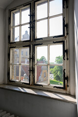 white painted wooden window frame with black hinges and corner brackets. Window in the old palace. view from the window