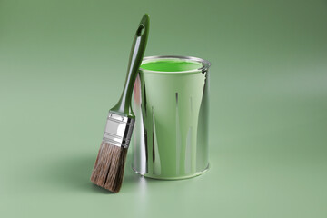 Can of paint and brush on light green background
