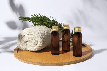 Fototapeta na wymiar Bottles of cosmetic products, rolled towel and rosemary on white background