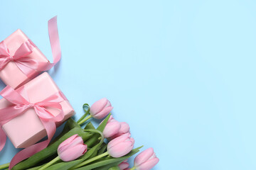 Beautiful gift boxes and pink tulip flowers on light blue background, flat lay. Space for text