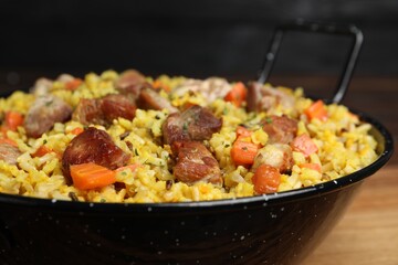 Delicious pilaf with meat and carrot on wooden table, closeup
