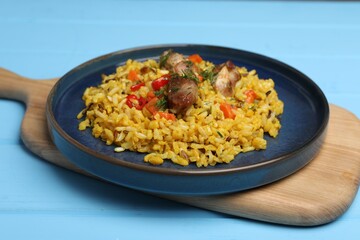 Delicious pilaf with meat, carrot and chili pepper on light blue wooden table, closeup