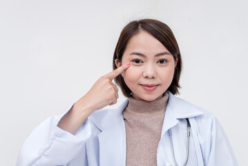 Portrait of a young and skilled doctor, medical student, intern posing while pointing at her head, thinking. Isolated on a white background.