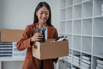 Close up Asian business office woman resignation, carrying her personal stuff, happy to leave her job or change job positions.