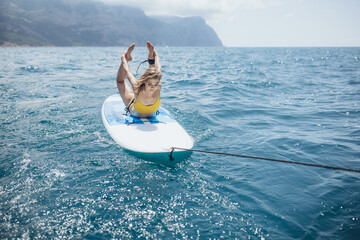 A woman practices yoga at the sea. SUP sports