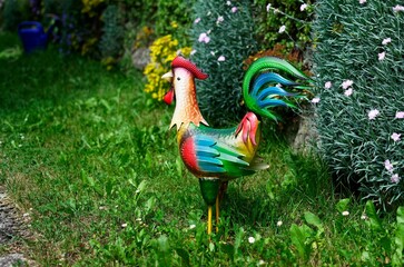 Vibrant red rooster lawn ornament figurine in a grassy field