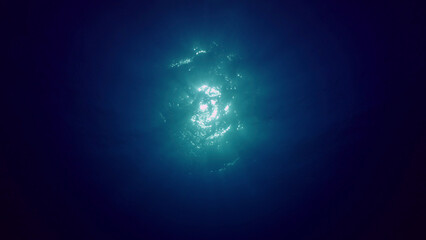 Naklejka na ściany i meble View of sun light from blue abyss, slow motion. Light filters down through blue water. Underwater sun rays in depth ocean. Underwater light, sun light shine under deep water with ripples on surface
