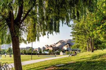 Obraz premium People sitting and relaxing on the grass, reading and relaxing, in the park of Milano CityLife district. 