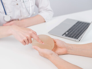 Caucasian woman and plastic surgeon touching and choosing breast implants. 