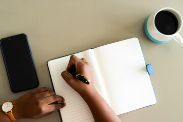 Hands of plus size african american woman taking notes in notebook at table