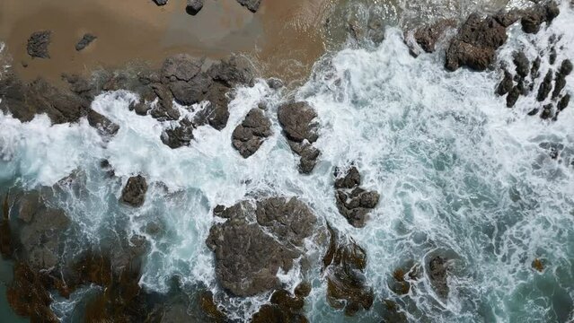 Drone view over sea waves covering a rough rocky coastline in Otago, New Zealand