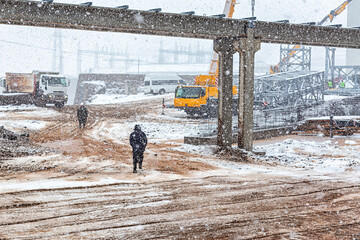 Construction site with snowy weather. Construction covers the processes involved in delivering buildings, infrastructure, industrial facilities, and associated activities through.