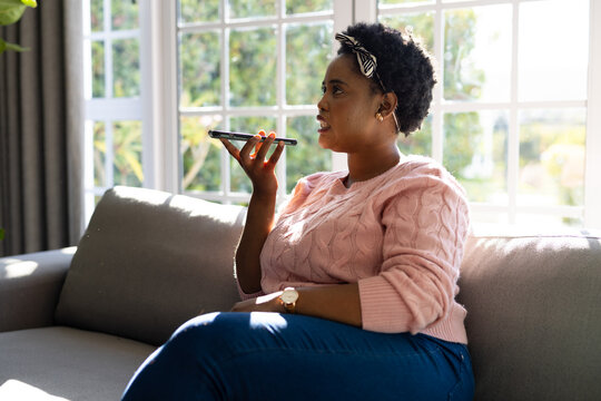 Plus size african american woman talking on smartphone in living room
