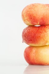 Closeup of fresh peaches arranged and stacked on top of each other on a white background