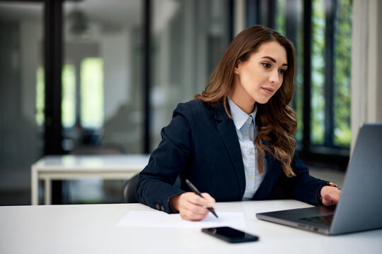 A hardworking female employee working on a laptop at the office table.