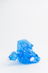 immagine con primo piano di bottigglie in PET riciclato vuote e accartocciate da smaltire su superficie bianca